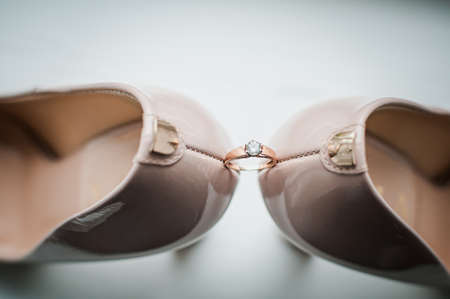 Pair of golden wedding rings between pair of a white shoesの写真素材