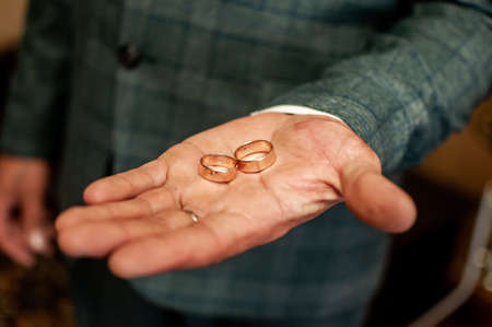 Groom holding golden wedding rings on the handの写真素材