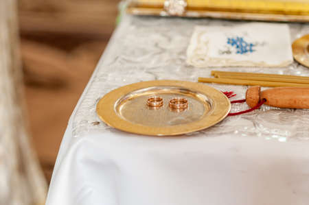 Pair of gold wedding rings on the golden plateの写真素材
