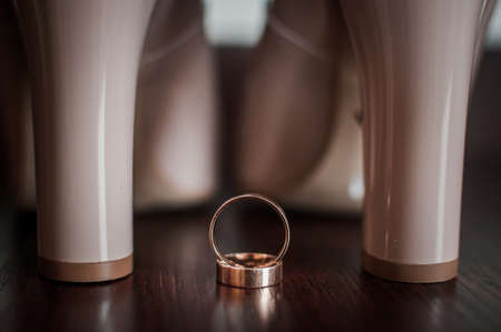 Pair of high heel shoes and gold wedding ringsの写真素材