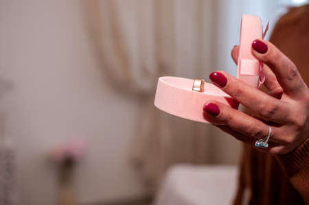 Couple of gold wedding rings in the pink box in the hand