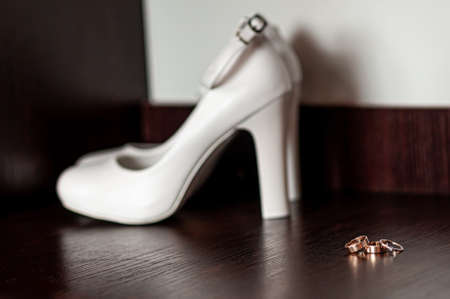 Three gold wedding rings and white high heel shoe on the table