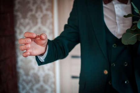 Groom holding golden wedding rings on the handの写真素材