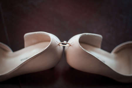 Golden wedding ring between pair of a white shoesの写真素材