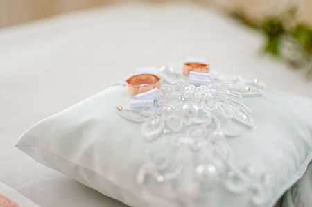 Pair of golden wedding rings on the white pillowの写真素材