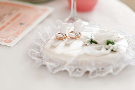 Gold wedding rings on the white rose backgroundの写真素材