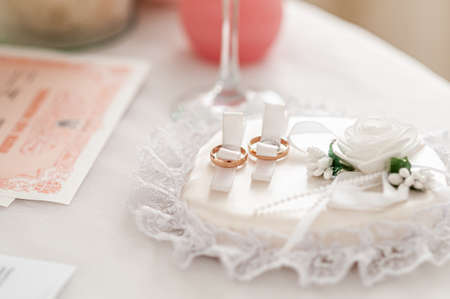 Gold wedding rings on the white rose backgroundの写真素材