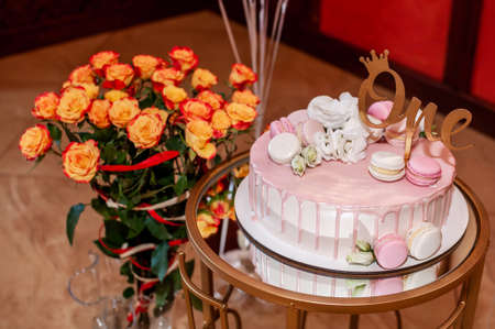 Festive cake on a stand and a bouquet of orange roses