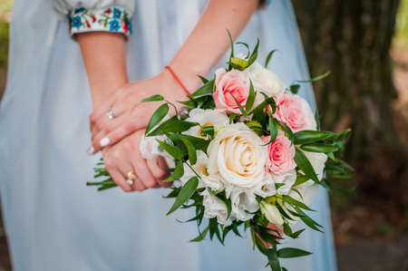 wedding bouquet in the hands of the bride of white and pink rosesの写真素材