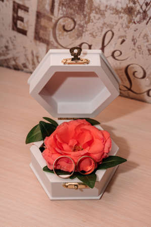 Wedding gold rings on an orange rose in a white box