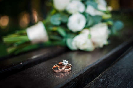 Wedding rings on a wooden stand against the background of the bride's bouquet
