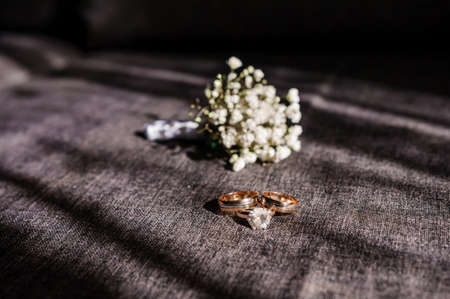 Groom's boutonniere, wedding gold rings on brown backgroundの写真素材