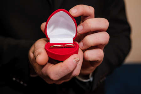 Wedding gold rings in a red box, wedding gold rings in the hands of the groomの写真素材