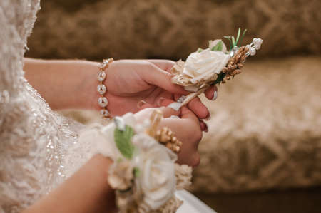 Boutonniere of the groom with white flowers in the hands of the bride