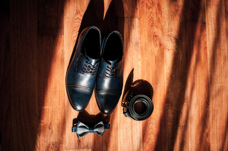Blue leather men's shoes, bow tie and belt lie on the floor. Groom's accessoriesの写真素材