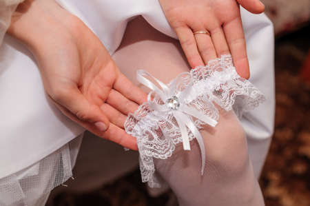 Garter of the bride on the leg of the bride