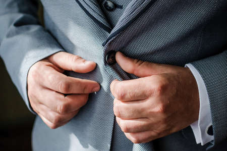 The man fasten a button on his jacket. The groom fasten a button on his jacketの写真素材