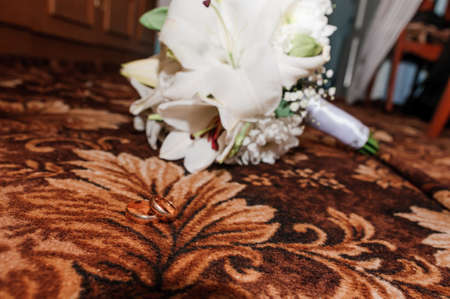Pair of wedding rings and bouquet with white flowersの写真素材