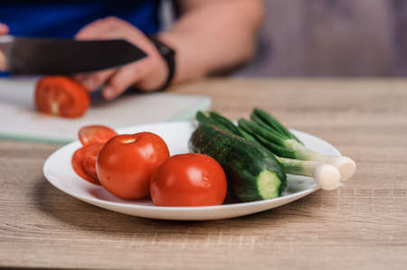 Tomatoes and cucumbers on a white plate on the tableの写真素材