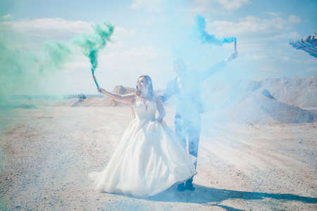 The guy and the girl hug and hold colored smoke in their handsの写真素材