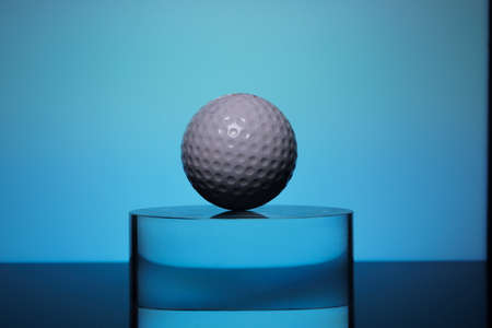 white golf ball on the transparent glass on blue backgroundの写真素材