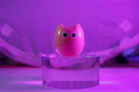 plastic owl toy on the glass cylinder color backgroundの写真素材