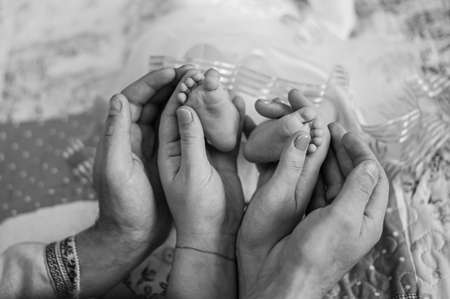 hands forming a heart frame for tiny feet of her newborn babyの写真素材