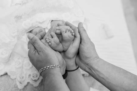 hands forming a heart frame for tiny feet of her newborn babyの写真素材