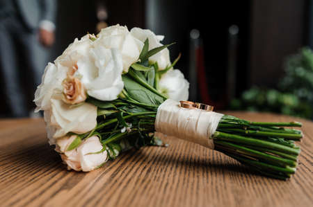 Wedding bouquet of fresh flowers, a pair of gold rings close-up. Wedding detailsの写真素材