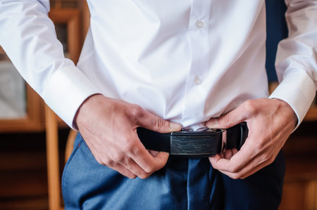 The groom tightens his belt. A man holding his hands on his beltの写真素材