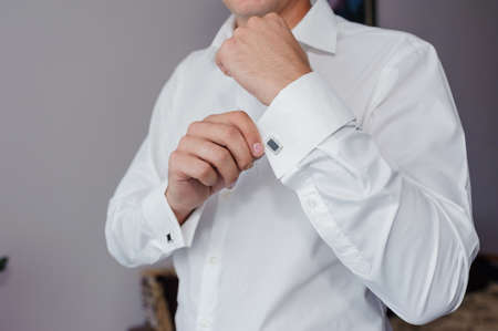 Man fastening a cuff-link on the shirt. Groom fastens cufflinks on the shirt