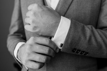 A groom fastening a cuff-link on the shirt. Men fastening a cufflink on their shirtの写真素材