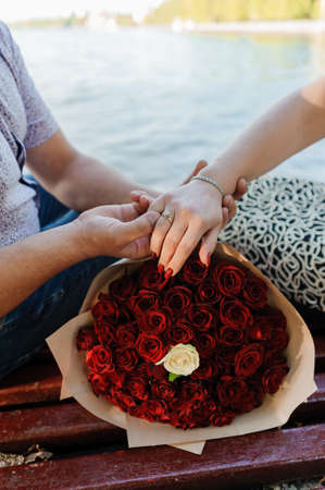 Bouquet of red roses, womens gold ring with a stone. Bouquet of red flowers. An offer of marriage