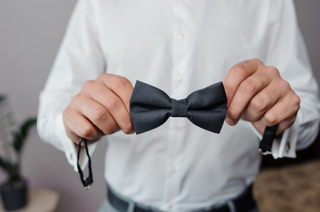 Black bow tie in the hands of the groom. Bow tie in the hands of a manの写真素材
