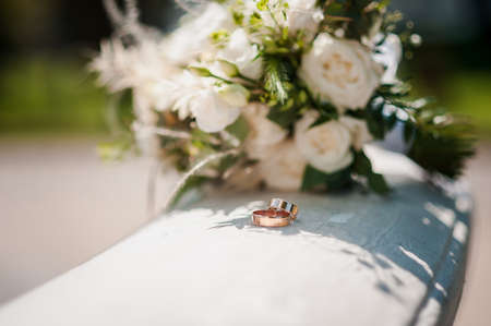 A pair of golden wedding rings on a background of white flowers