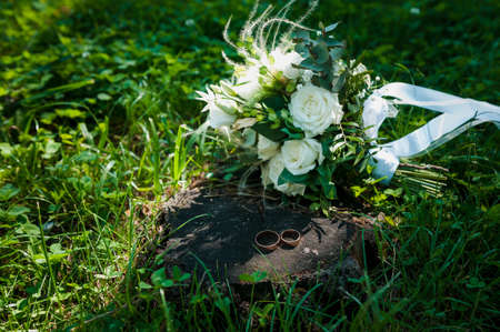 A pair of golden wedding rings on a background of white flowersの写真素材