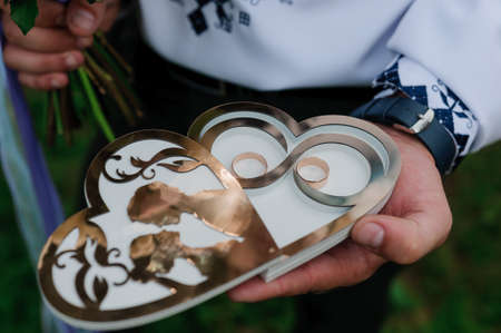 A pair of gold wedding rings on a heart-shaped standの写真素材