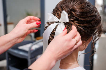 The morning of the bride. Girl makes a stylish hairstyle, a friend helps the bride, a beautiful hair ornament, preparation for a party, close-up hairstyleの写真素材