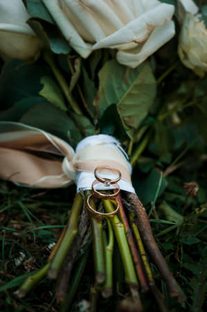 Golden wedding rings on the brides bouquet of white flowersの写真素材
