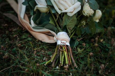 Golden wedding rings on the brides bouquet of white flowersの写真素材