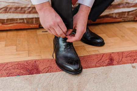 Man tying shoelaces on leather shoesの写真素材