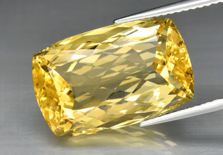 Natural gemstone yellow citrine in tongs on a background