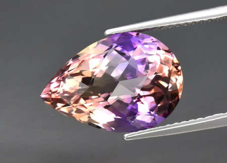 Natural gemstone colored ametrine in thongs on a background. Natural Bolivian bicolor yellow purple...