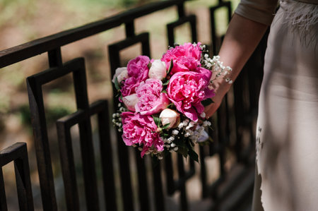 A bouquet of flowers in the hands of the bride. A bouquet of flowers with pink peonies in the hands of a womanの写真素材