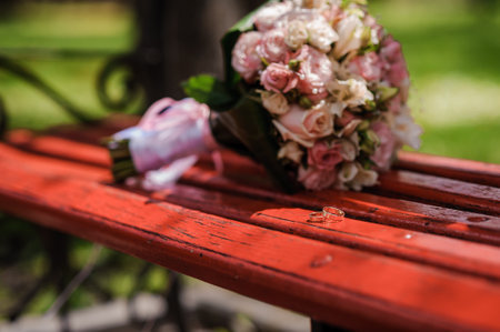 Golden wedding rings, in the background the bride's bouquet of multi-colored flowers.の写真素材