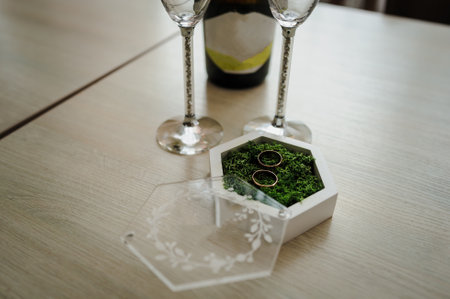 Two gold wedding rings on green moss in a white wooden box.の写真素材