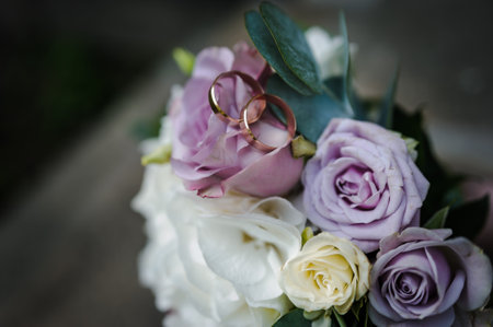 A pair of gold wedding rings on a bride's bouquet with colorful flowers.の写真素材