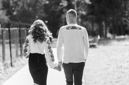 The boy and the girl walk holding hands. Man holding woman's hand.