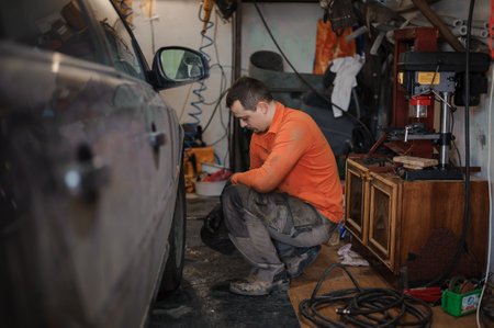 Mechanic man repairs the undercarriage of the car. A man repairs a car in a garage. Car wheel repairの写真素材