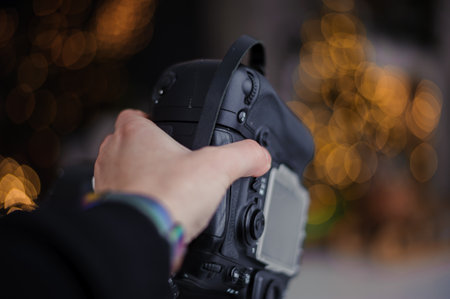 Black camera in woman's hand, beautiful bokeh in the backgroundの写真素材